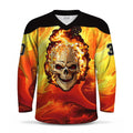 A long-sleeve V-neck hockey jersey with a black shoulder yoke and a vivid graphic print of a skull with flames on the front, set against a yellow and orange flame pattern. The jersey has black numbers on the sleeves.