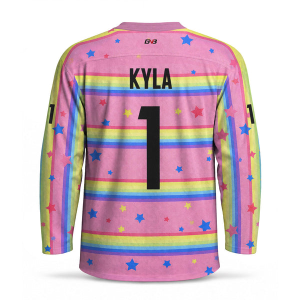 A long-sleeve hockey jersey shown from the back, featuring a pink base with horizontal rainbow stripes, scattered blue and pink stars, and personalized name 'KYLA' and number '1' in black.