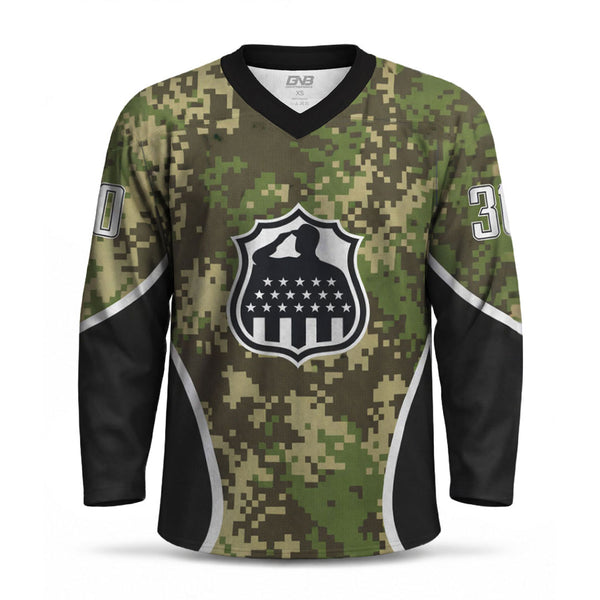 A long-sleeve hockey jersey with a green and brown digital camouflage pattern, black V-neck and sleeve panels, white side stripes, a large shield crest with a saluting soldier and stars-and-stripes motif on the chest, and partial white numbers on the sleeves.