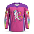 A long-sleeve hockey jersey with a bright pink body and purple shoulders, featuring a cartoon dancing unicorn graphic on the chest and rainbow-striped number panels on both sleeves.
