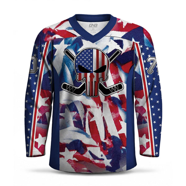 A long-sleeve hockey jersey with a patriotic red, white, and blue American flag star pattern, featuring a central skull graphic with crossed hockey sticks and a U.S flag.