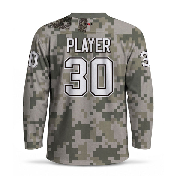 A long-sleeve hockey jersey shown from the back, featuring a digital camouflage pattern in shades of olive green, gray, and beige. The back is printed with player's name and number in white with black outlines.